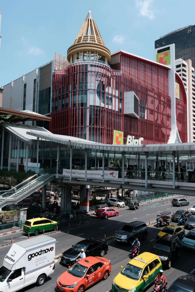  A crowded city street showcasing busy pedestrians and cars, with a visible sign pointing to Big C Supermart.