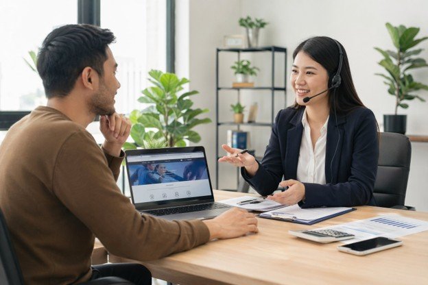 A man and woman sit at a table with a laptop, discussing strategies to negotiate their internet bill.